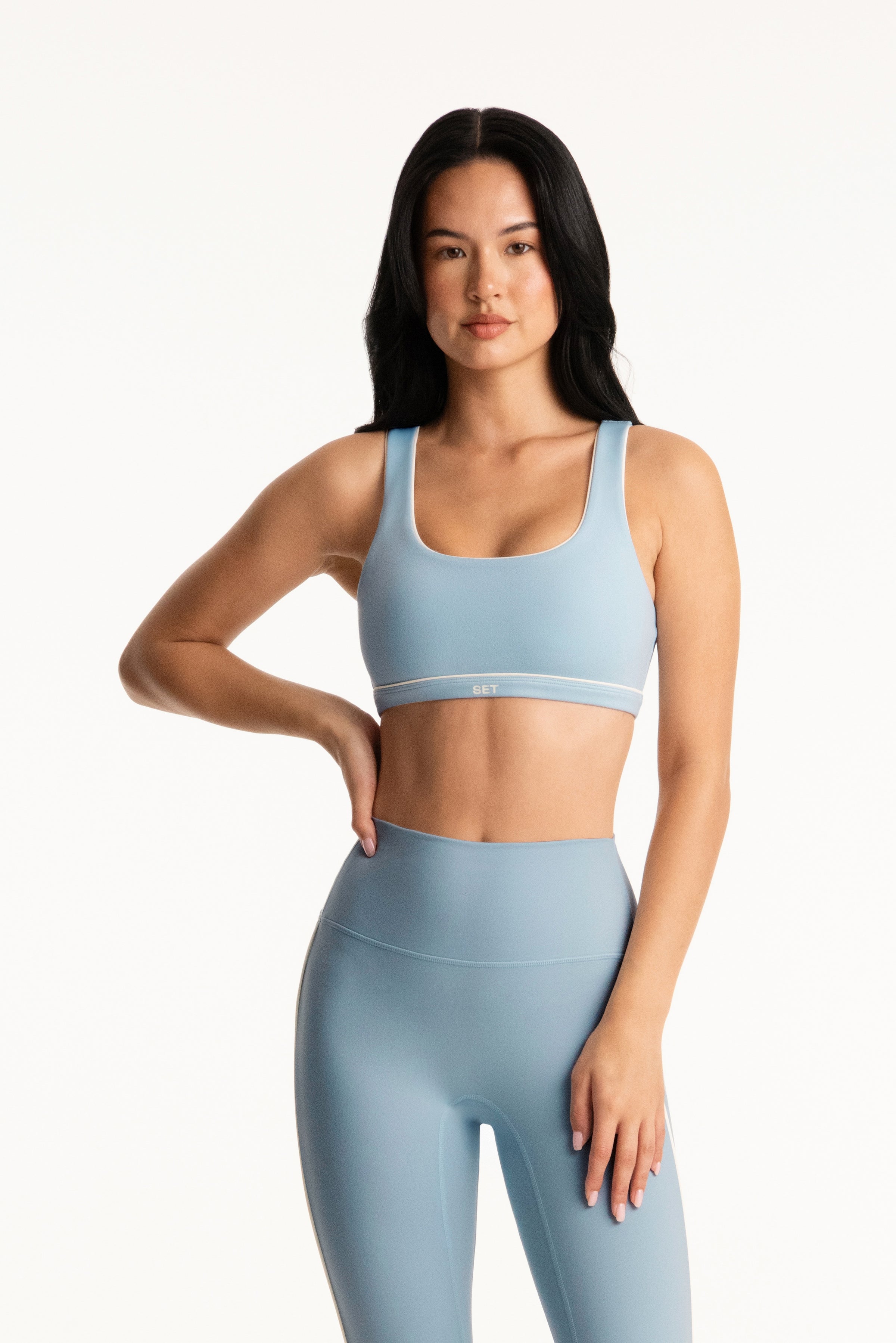 Girl wears light blue sports bra on white background 