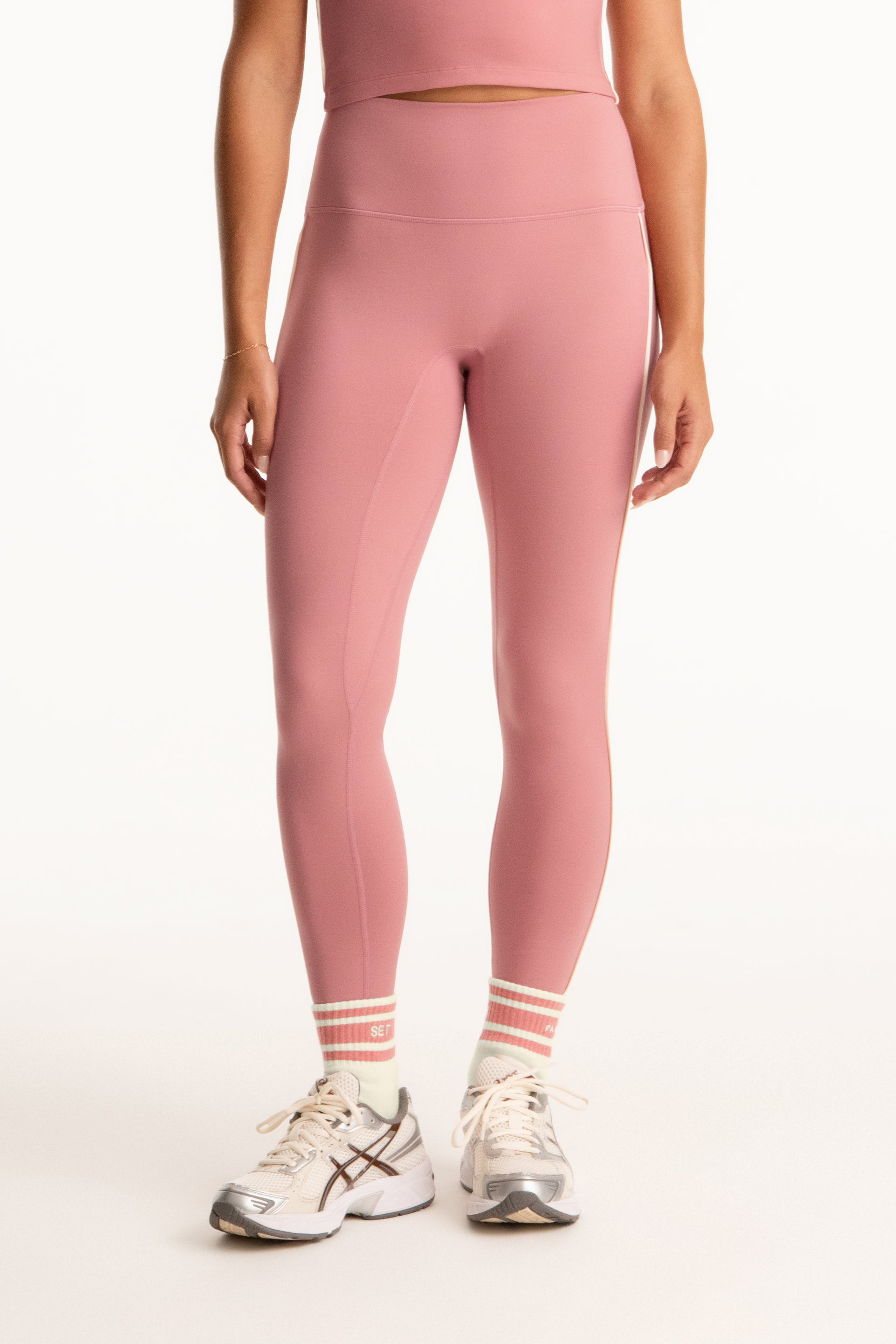 Person wearing pink athletic leggings and white sneakers on a white background <model-info>Presley wears a size S and is 5’6”, 26” waist, 33” bust.</model-info>