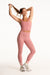 Woman in pink athletic wear stretching on a white background