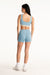 Woman wearing a light blue sports bra and shorts set on a white background
