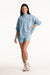 Woman wearing a light blue oversized sweatshirt and shorts on a white background