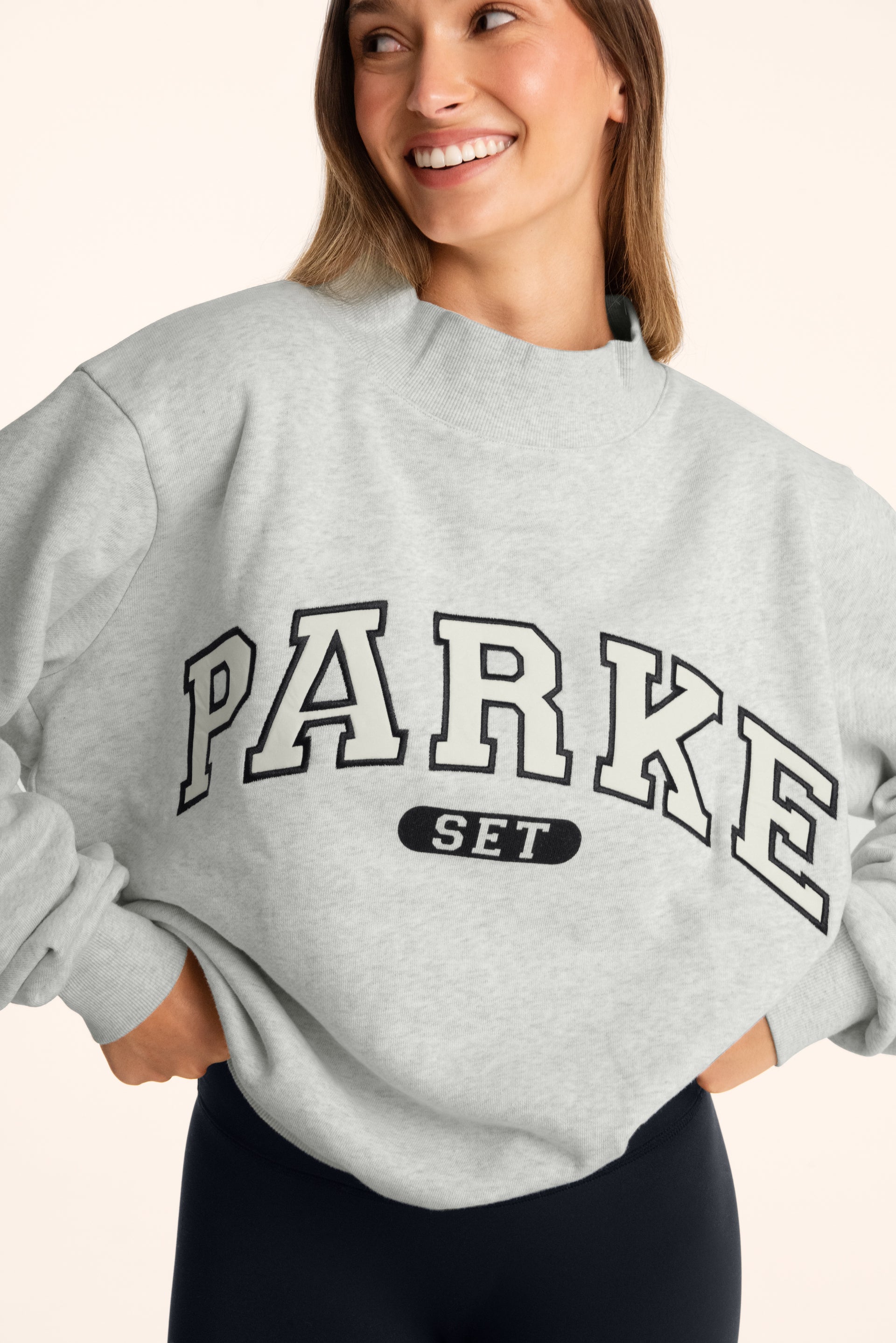 Person wearing a gray sweatshirt with 'PARKE SET' text on a plain background