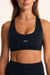 Black sports bra with 'SET' logo worn by a person on a beige background
