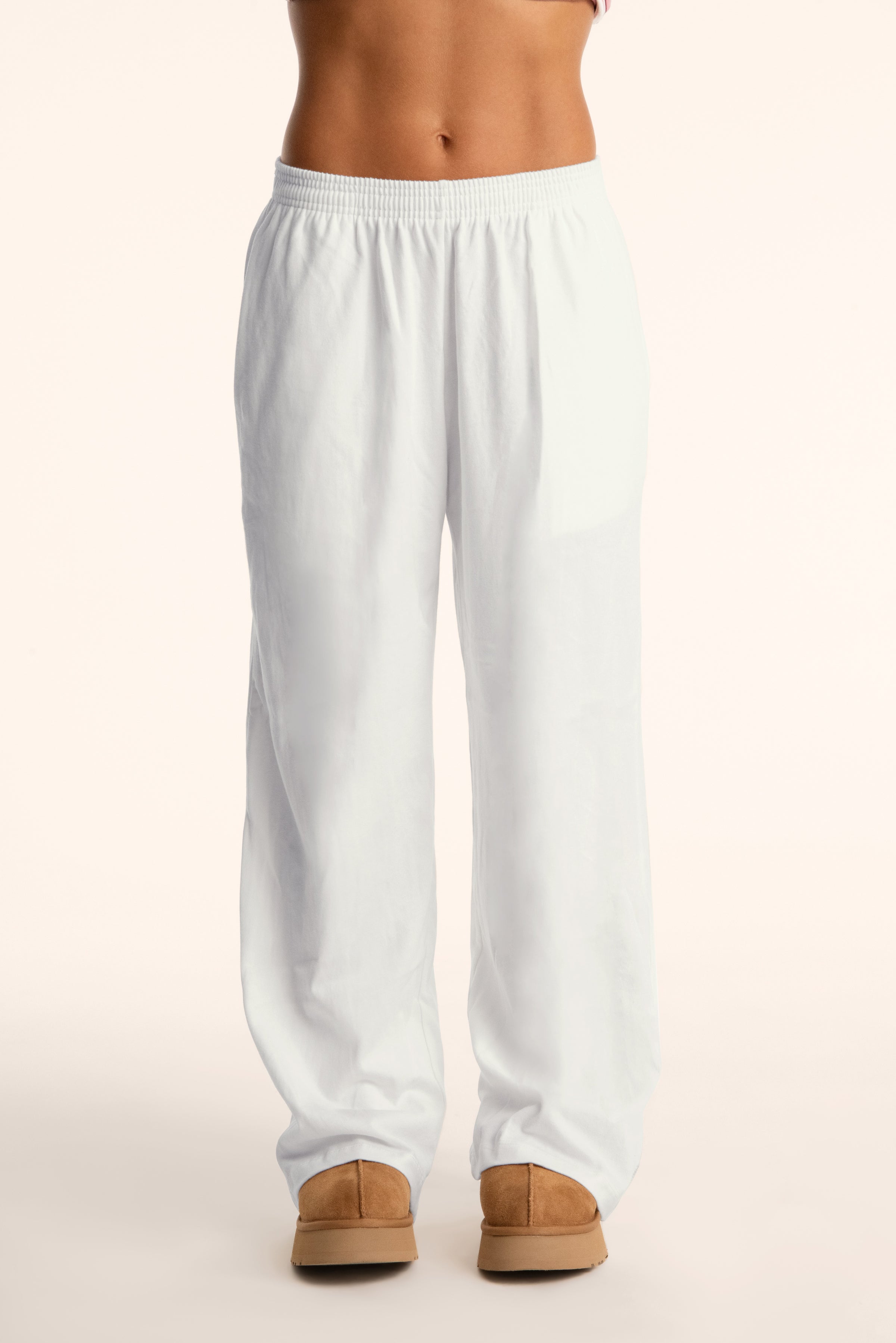 White pants worn by a person on a plain background 