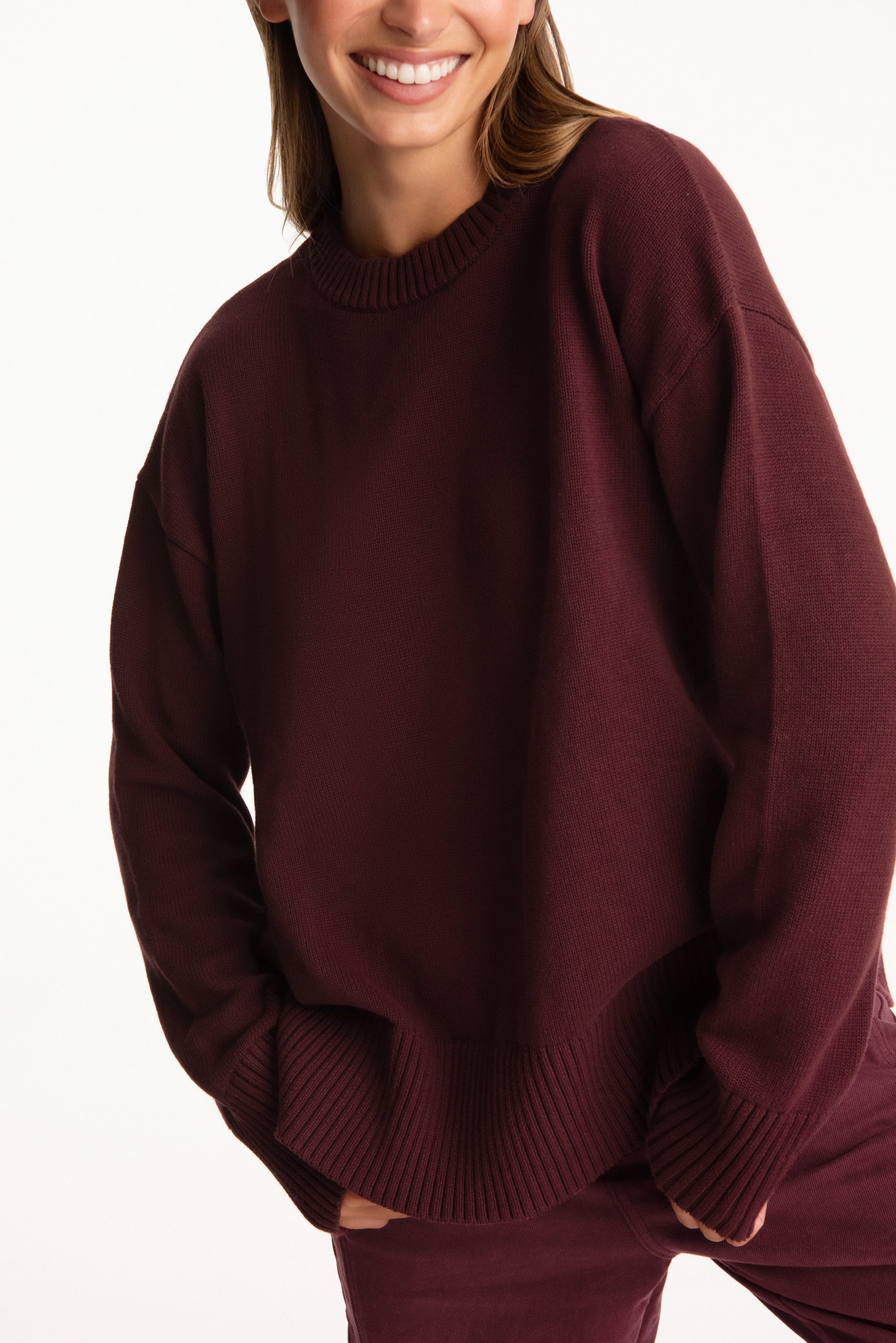 Person wearing a maroon sweater on a white background
