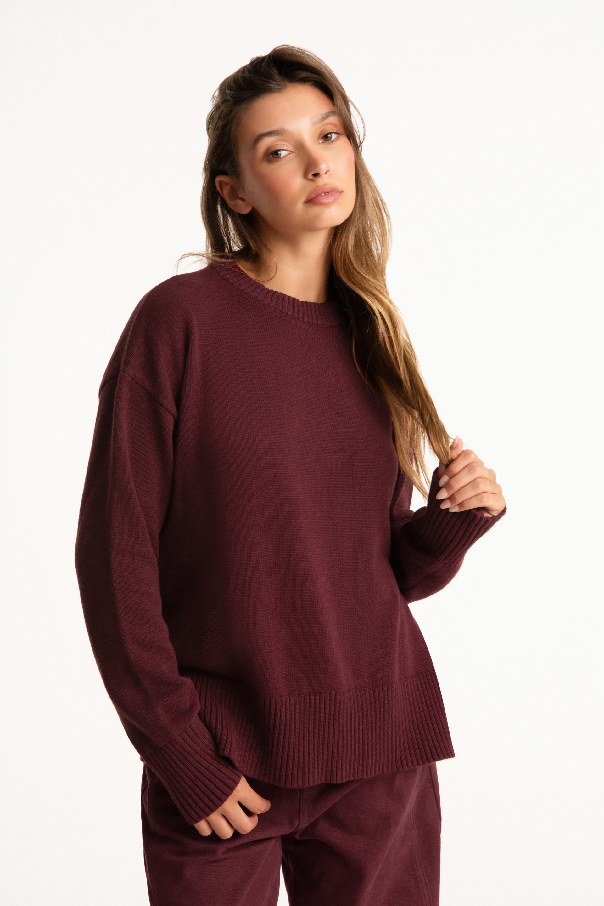 Woman wearing a burgundy sweater and pants on a white background <model-info>Presley wears a size S/M and is 5’6”, 26” waist, 33” bust.</model-info>