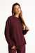 Woman wearing a burgundy sweater and pants on a white background <model-info>Presley wears a size S/M and is 5’6”, 26” waist, 33” bust.</model-info>