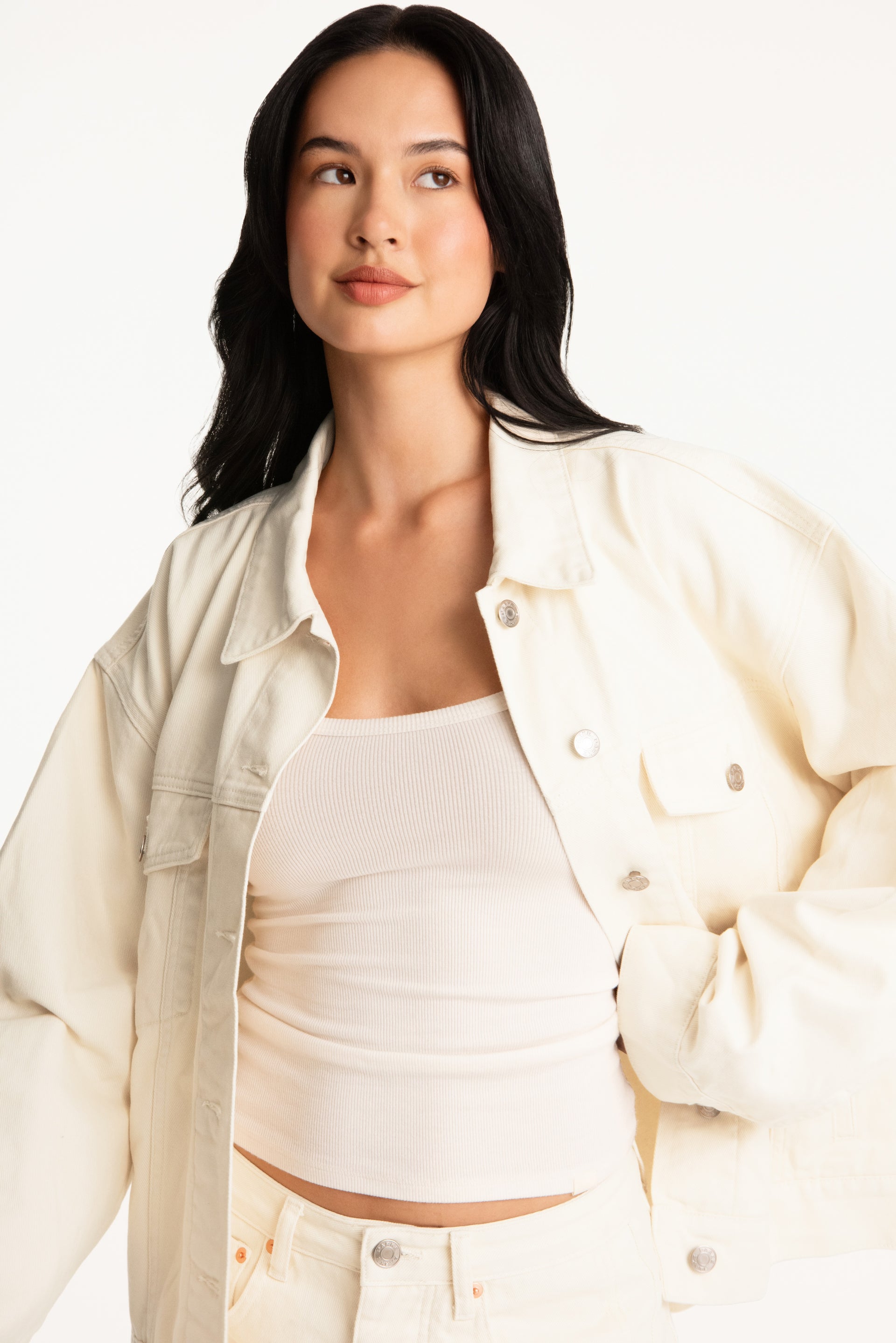 Woman wearing a light-colored jacket over a white top on a plain background