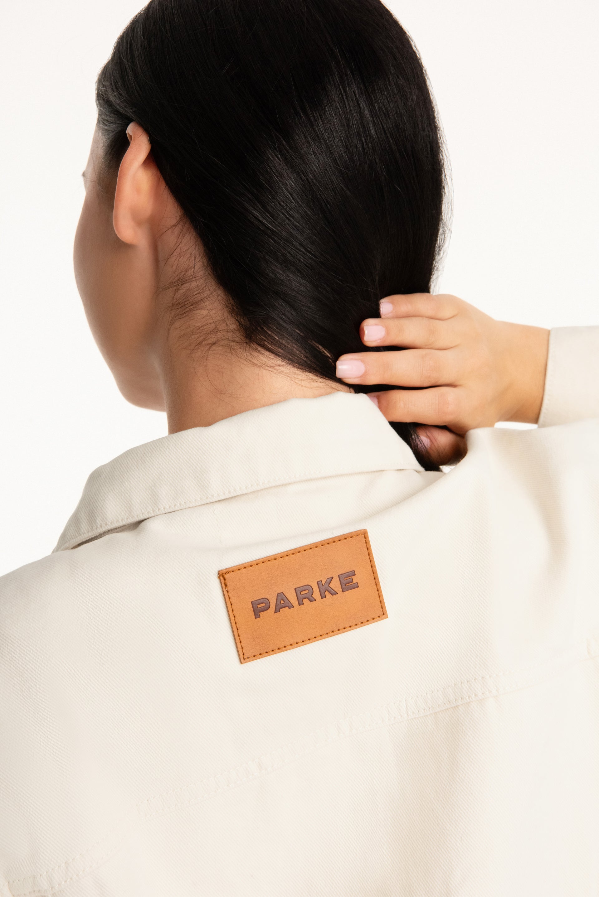 Person wearing a beige jacket with a 'PARKE' label on a white background