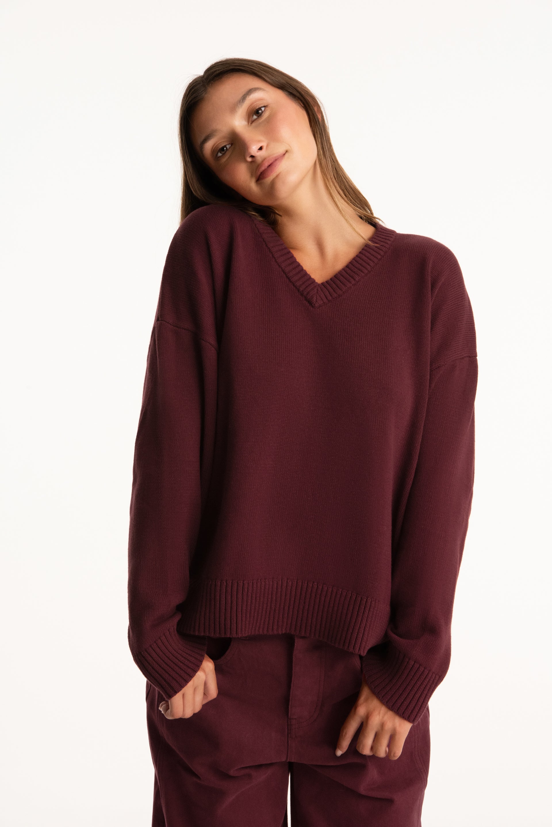 Woman wearing a burgundy sweater and pants on a white background <model-info>Presley wears a size S/M and is 5’6”, 26” waist, 33” bust.</model-info>