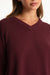 Close-up of a person wearing a burgundy sweater with a neutral background