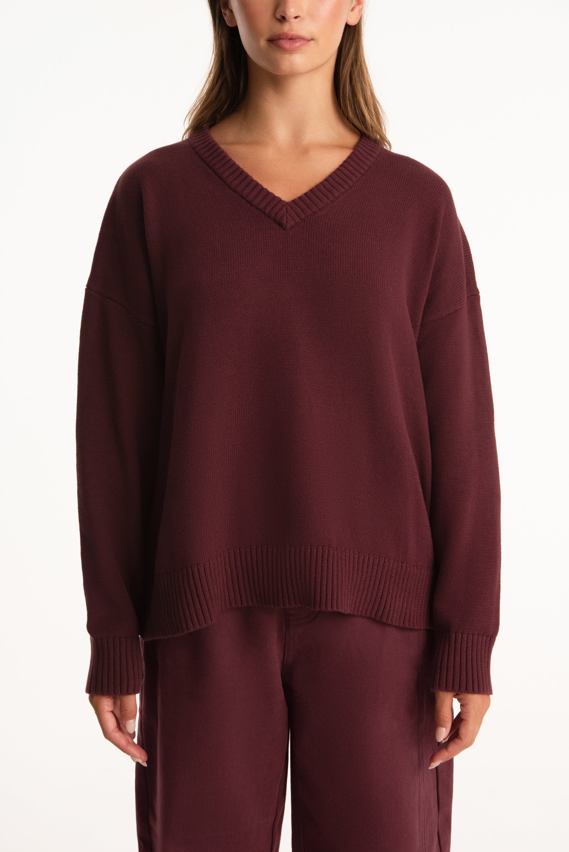 Maroon sweater worn by a person on a white background