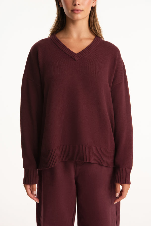 Maroon sweater worn by a person on a white background
