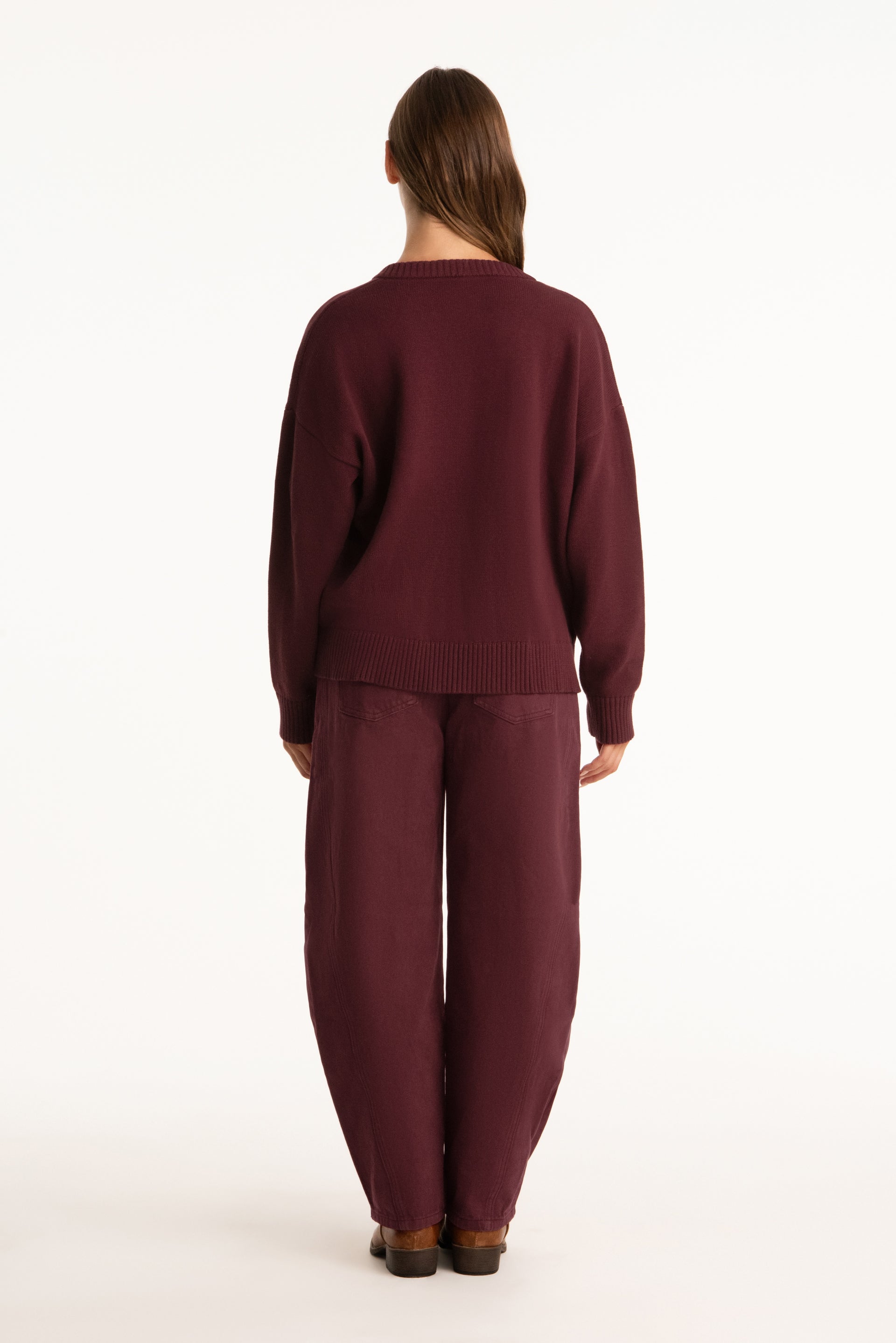 Person wearing a burgundy sweater and pants on a white background