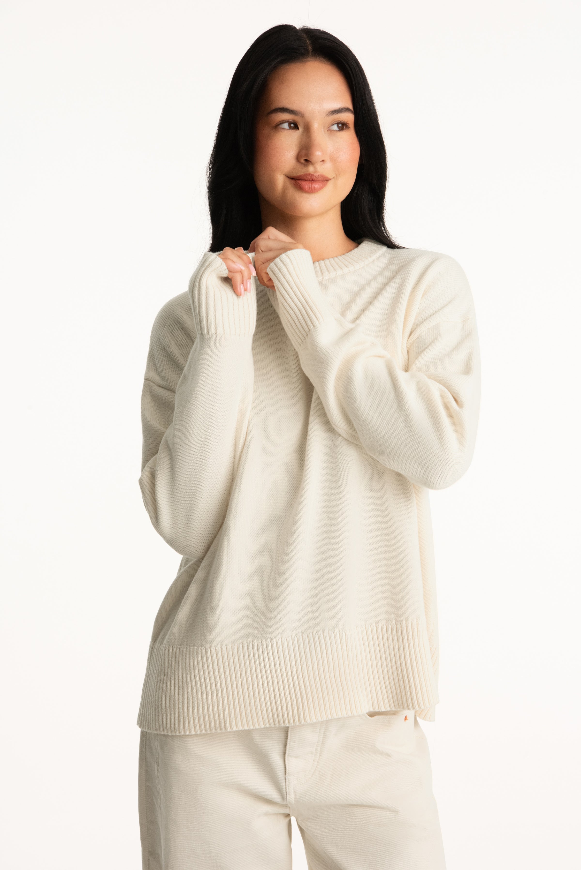Woman wearing a cream sweater and pants on a white background 