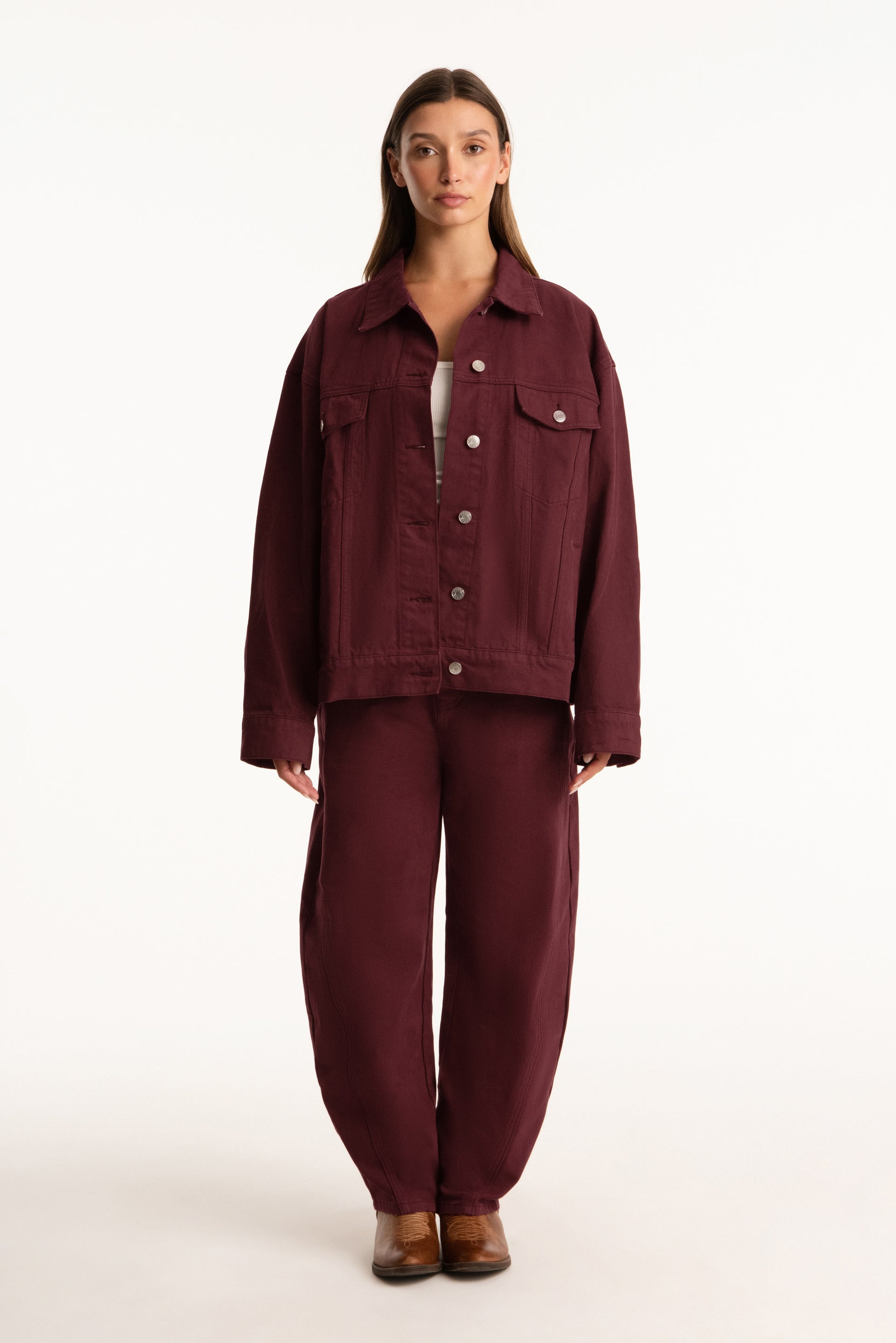 Person wearing a burgundy jacket and pants on a white background <model-info>Presley wears a size S/M and is 5’6”, 26” waist, 33” bust.</model-info>