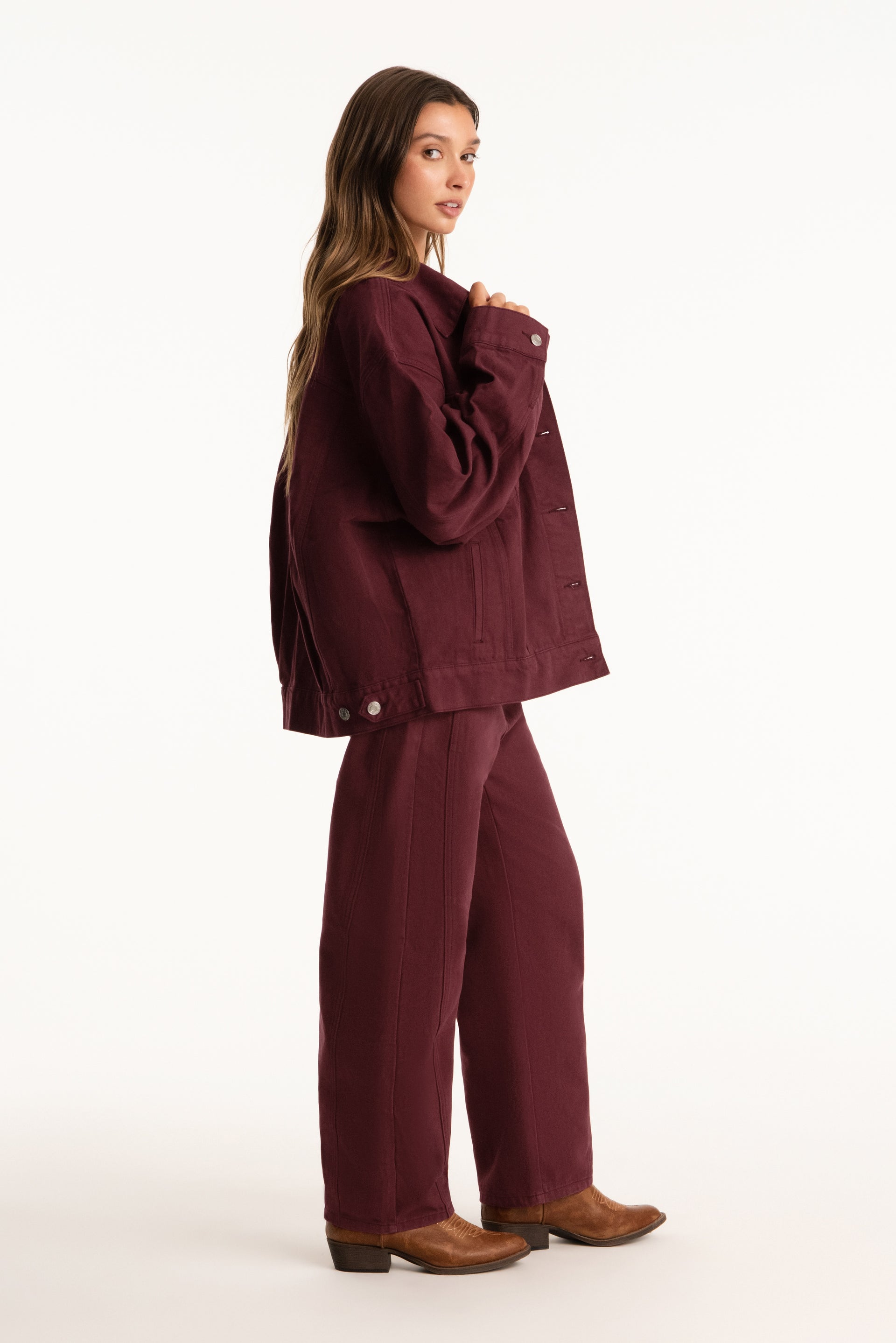 Woman wearing a burgundy jacket and pants on a white background