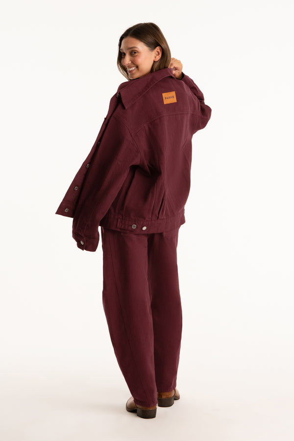 Woman wearing a burgundy jacket and pants on a white background