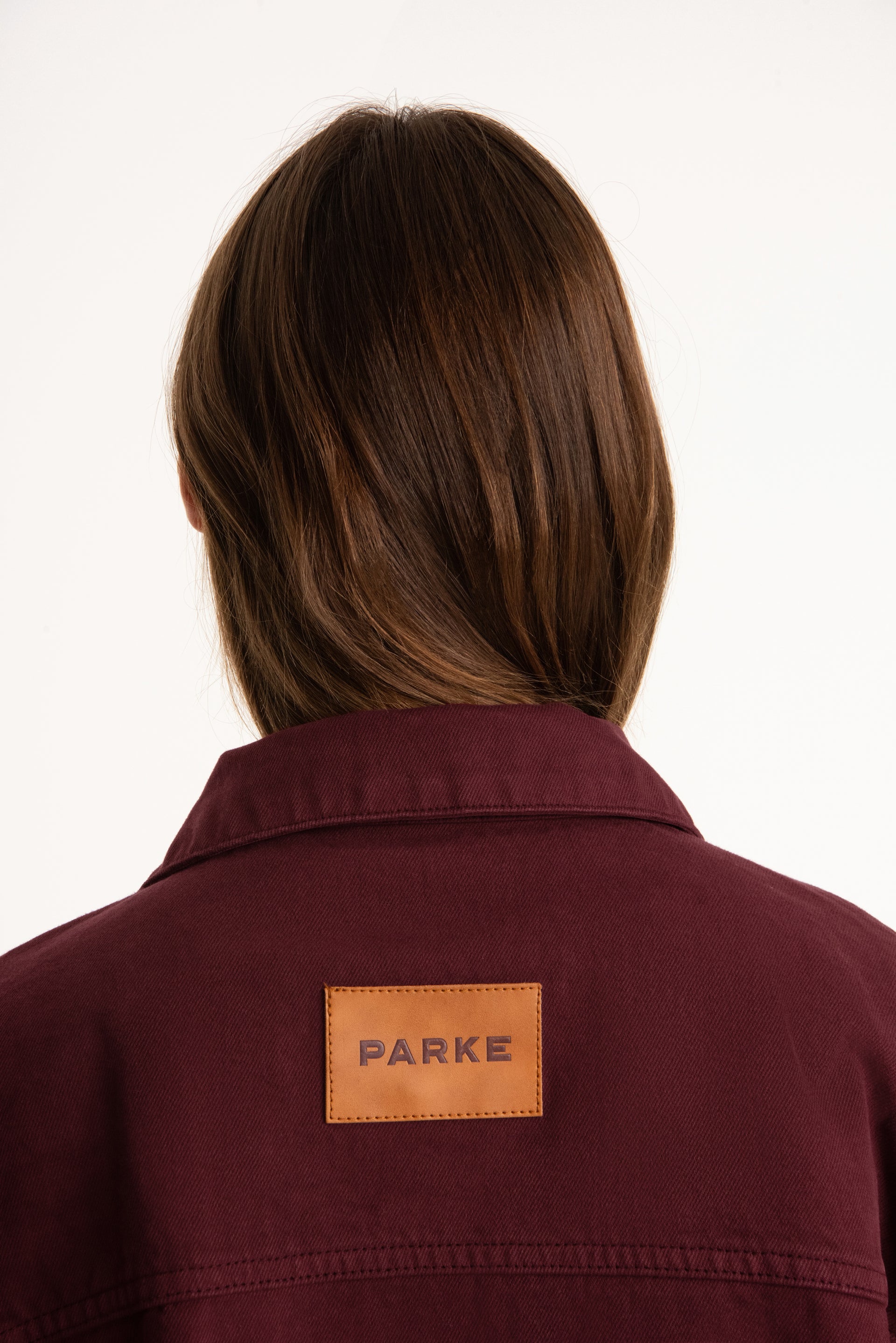 Person wearing a maroon jacket with a 'Parke' patch on a white background