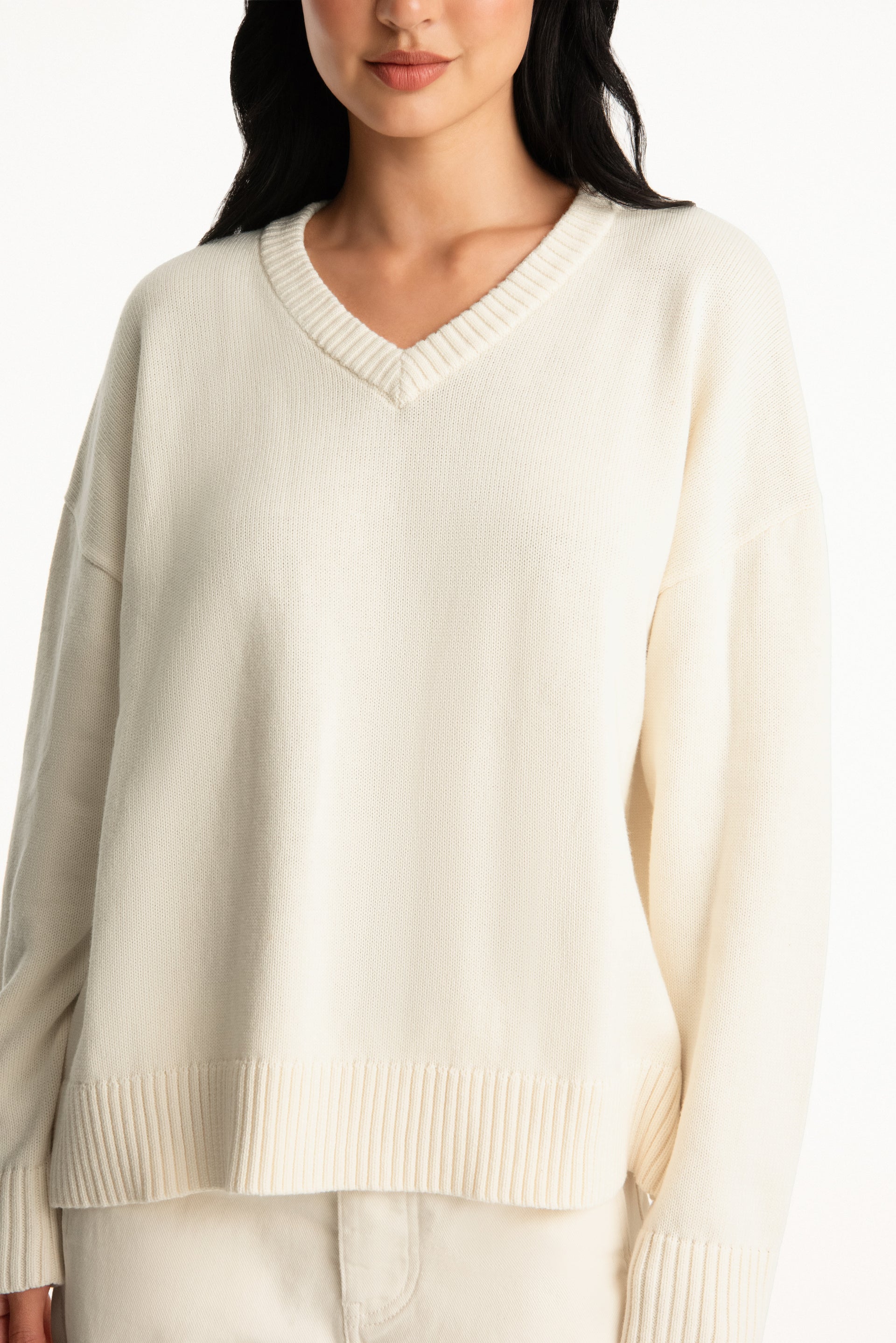 Woman wearing a cream-colored sweater against a white background