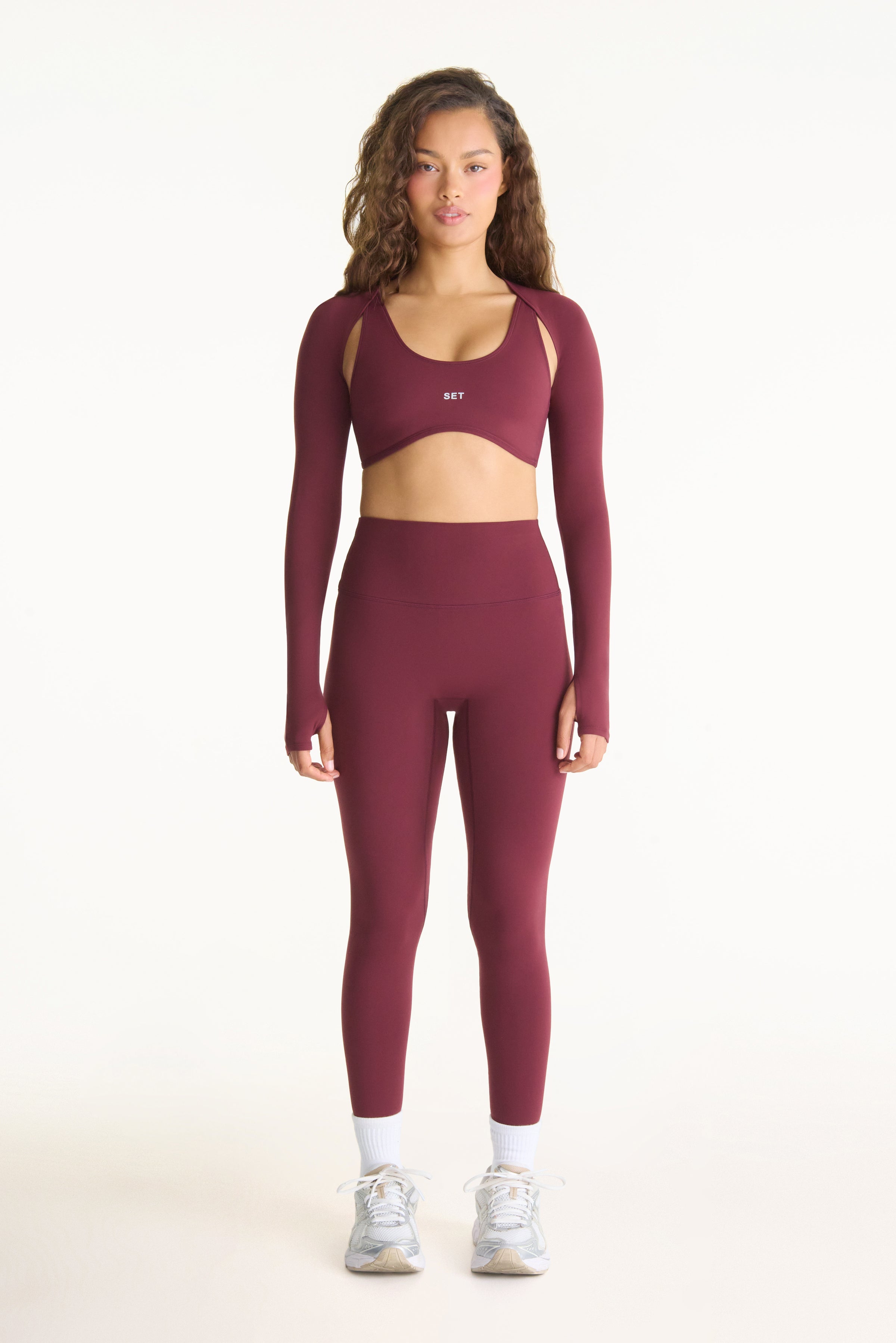 Woman wearing a burgundy athletic outfit on a white background