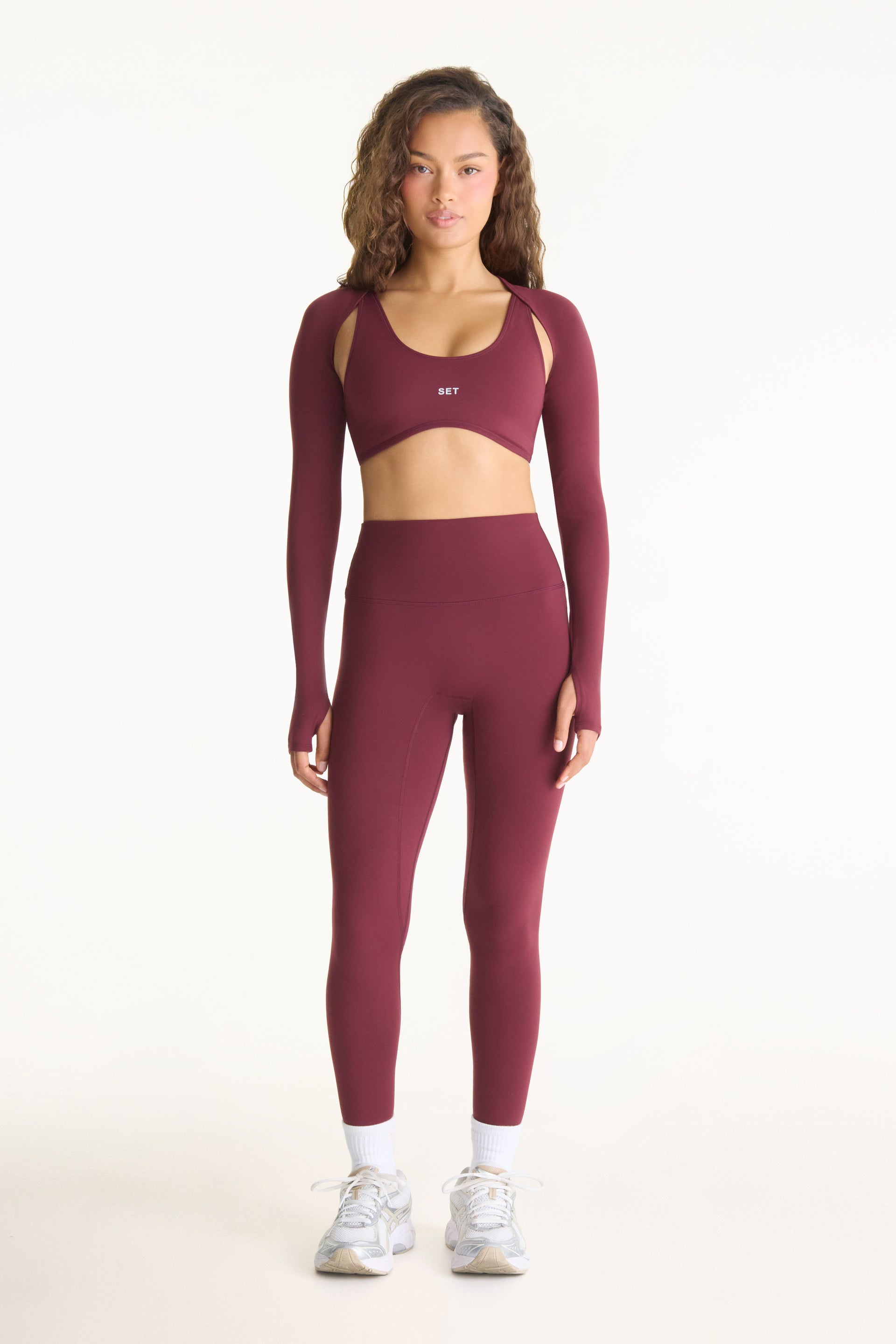 Woman wearing a burgundy athletic outfit on a white background