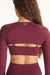 Maroon athletic top with long sleeves and cut-out design on a plain background
