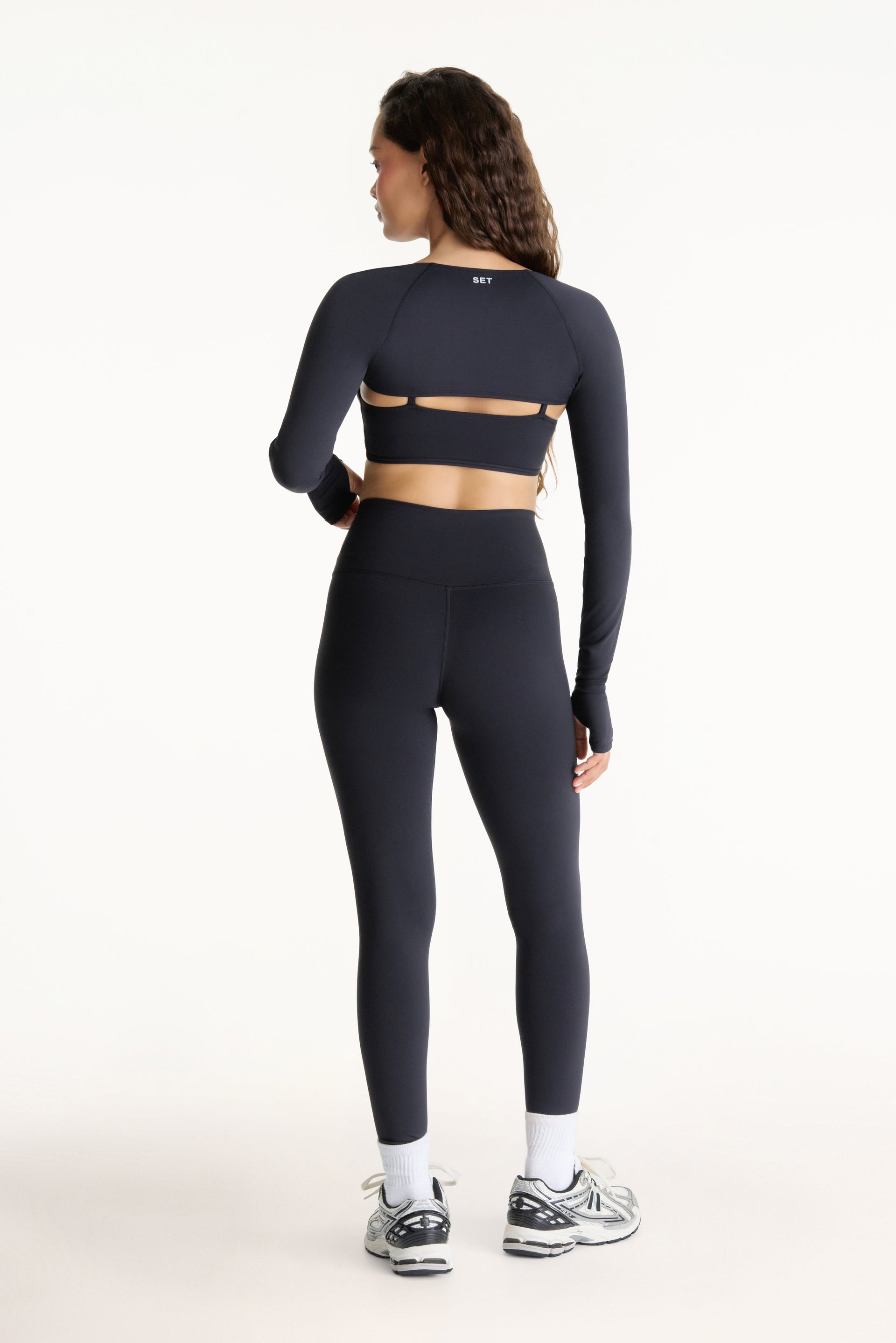 Person wearing a black athletic outfit with cut-out design on a white background