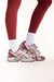 Red and white running shoes worn with red leggings on a white background