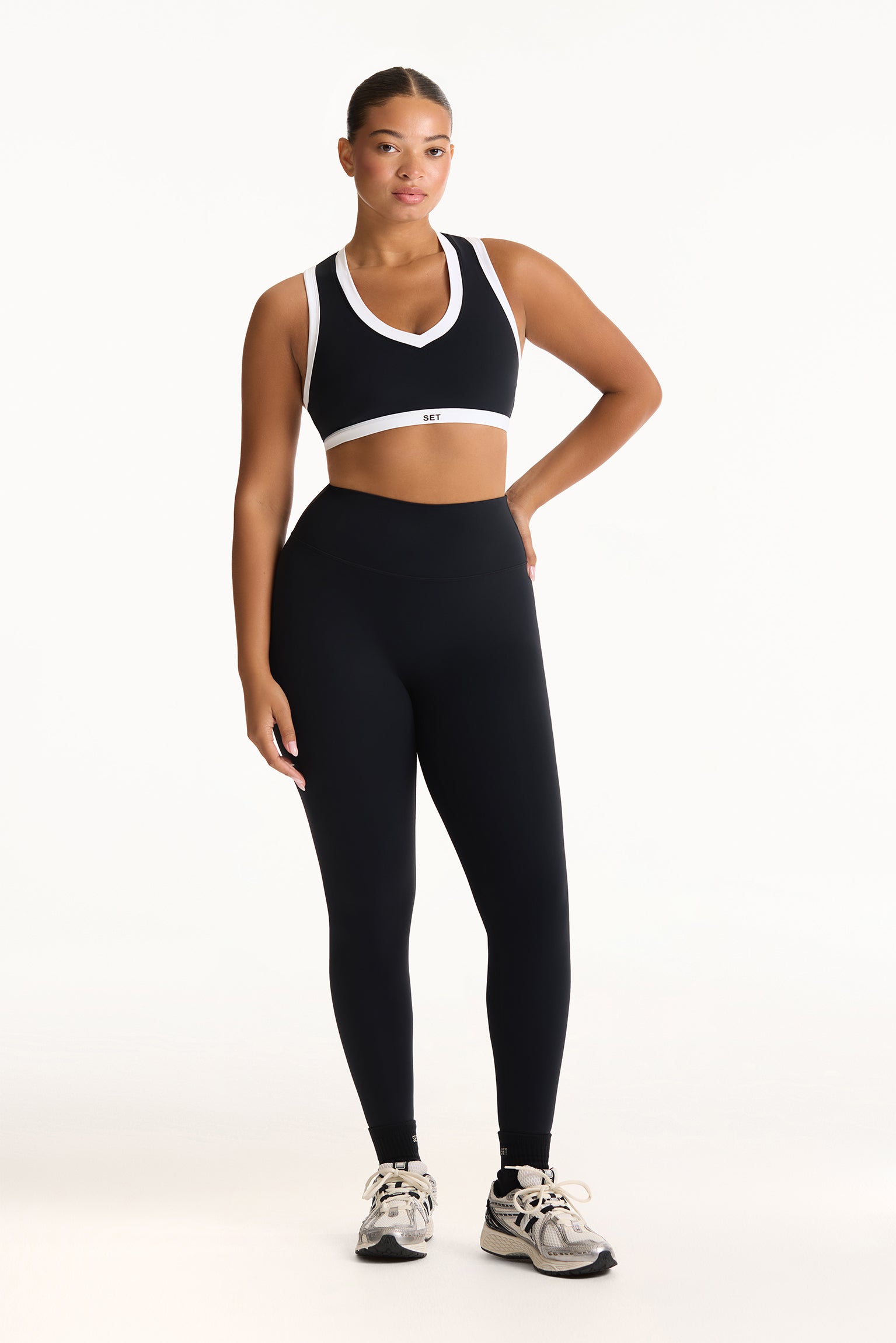 Woman wearing a black sports bra and leggings with a white background