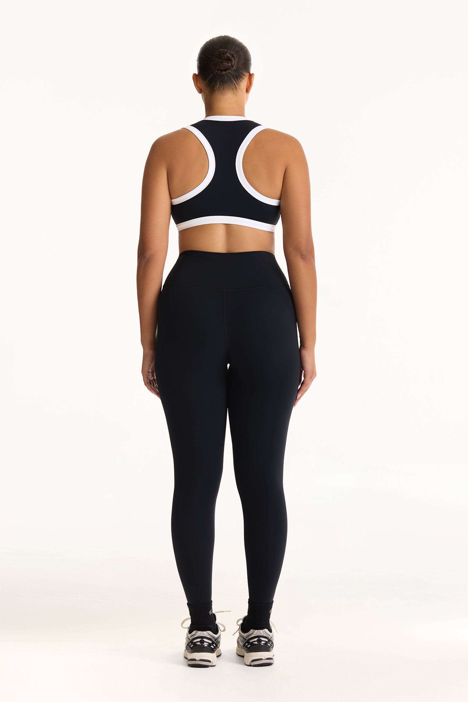 Person wearing a black sports bra and leggings set on a white background