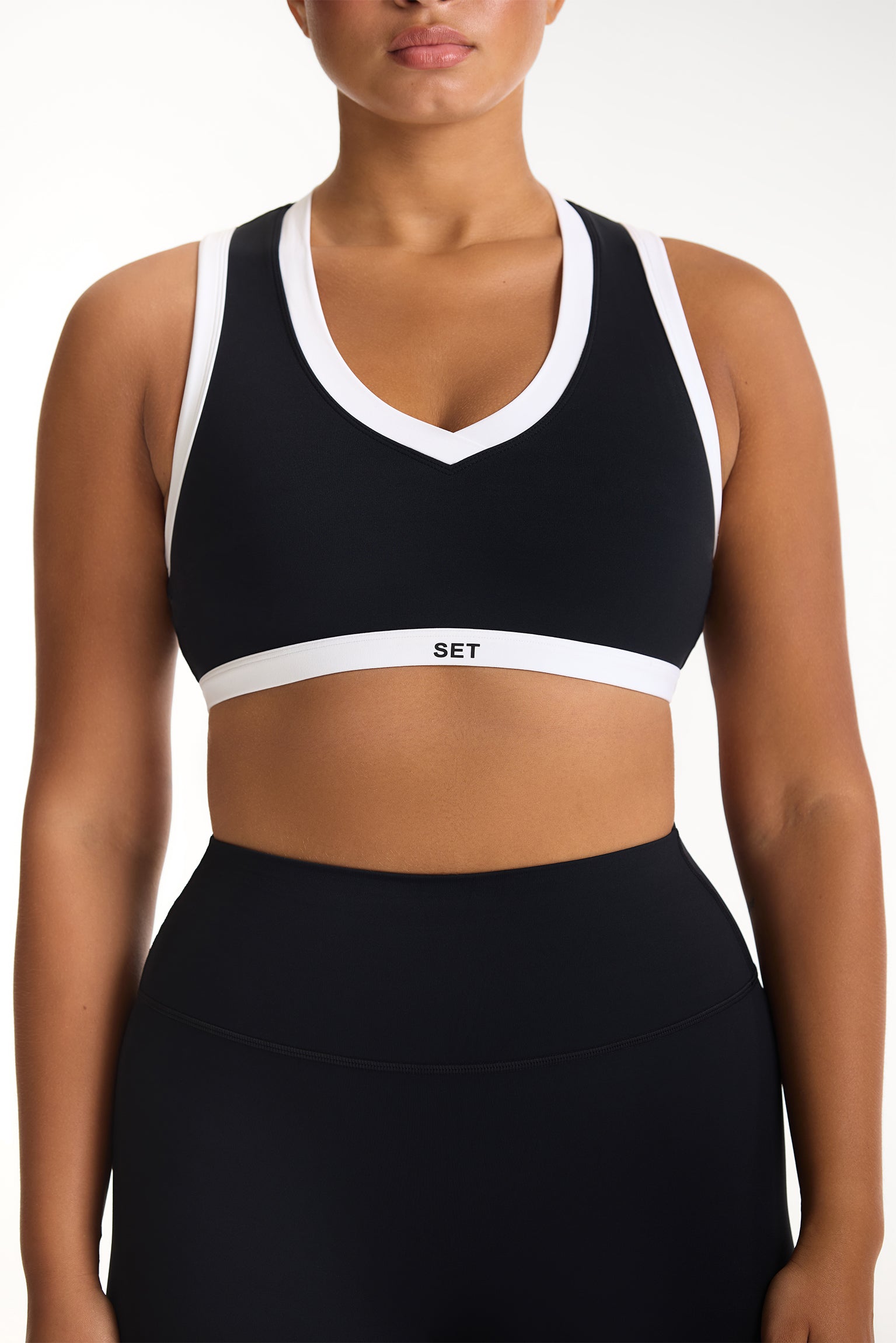 Black sports bra with white accents worn by a person on a white background