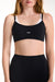 Black sports bra with white accents worn by a model on a plain background