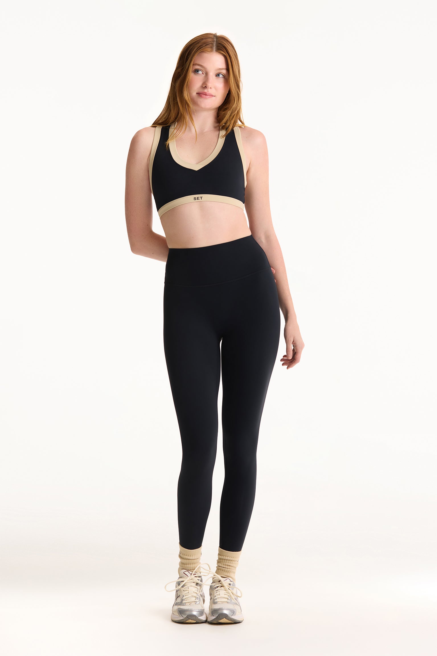 Woman wearing a black sports bra and leggings on a white background