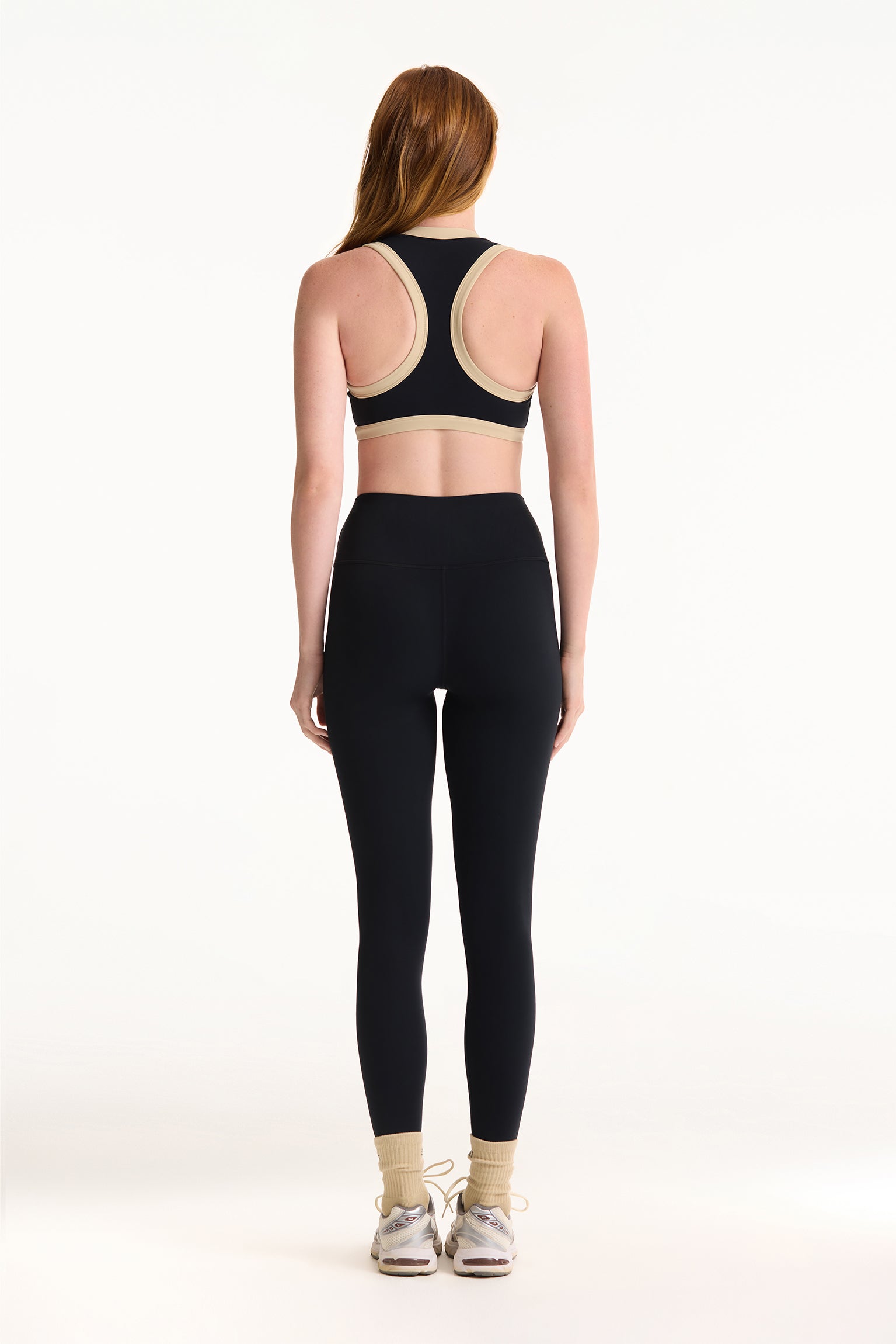 Person wearing a black sports bra and leggings on a white background