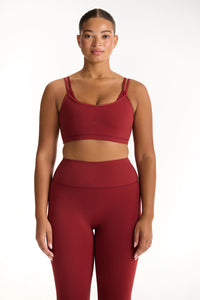 Woman wearing a red sports bra and leggings set on a white background 