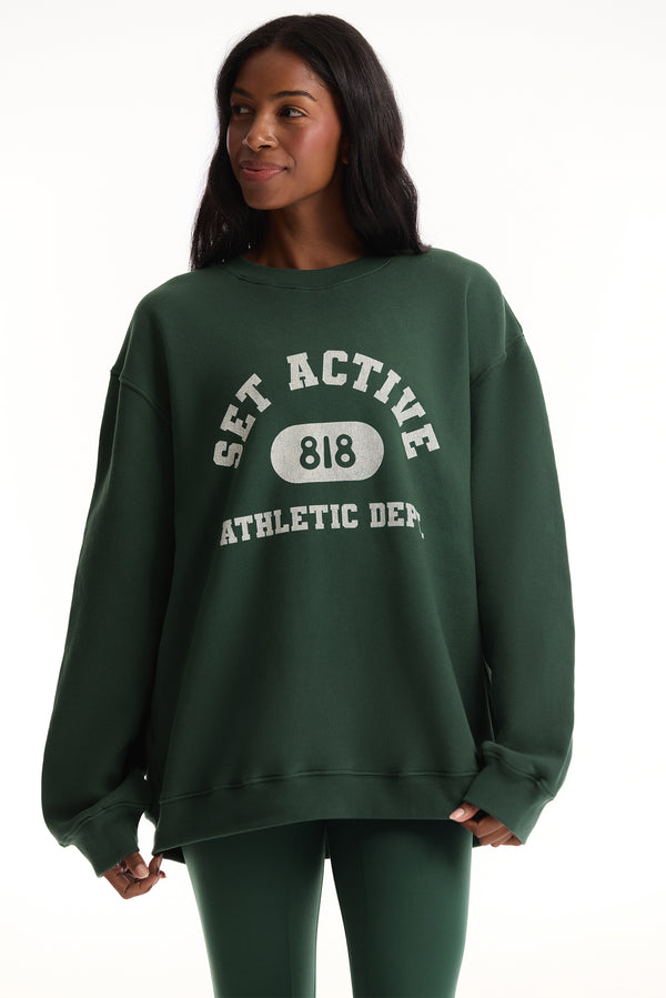Woman wearing a green sweatshirt with 'SET ACTIVE' text on a white background 