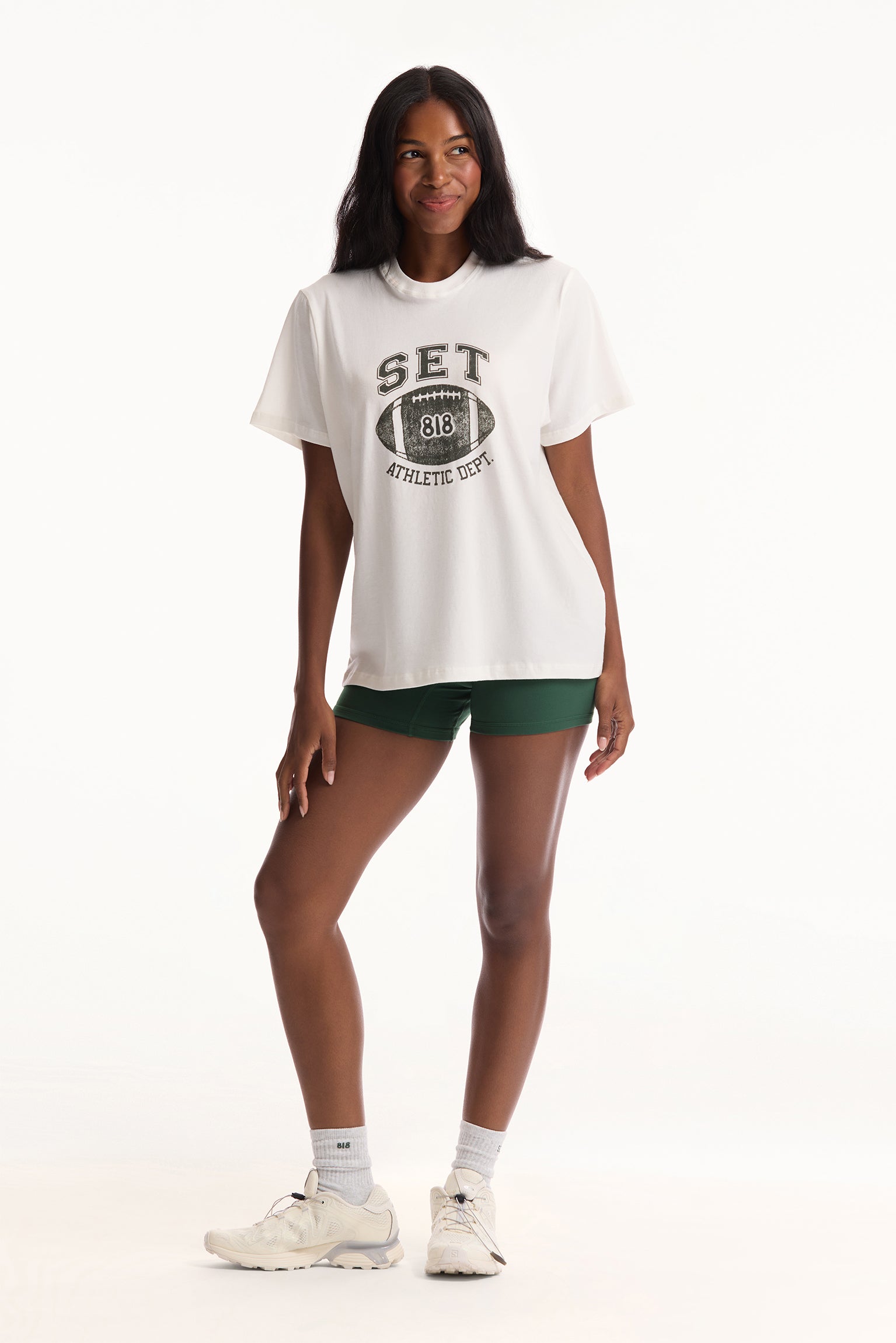 Woman wearing a white t-shirt with text and green shorts on a white background
