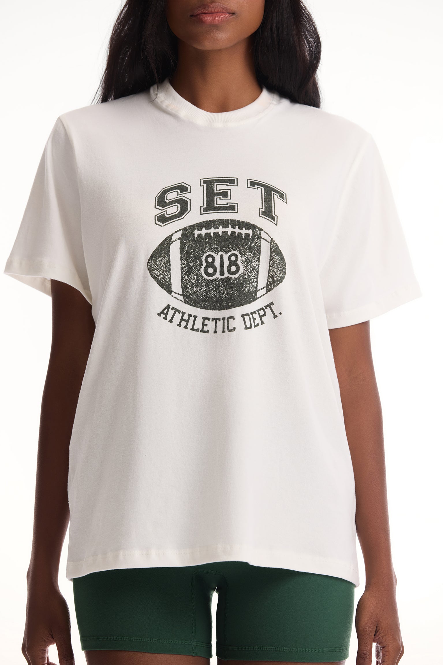 White t-shirt with football graphic and text worn by a person on a white background