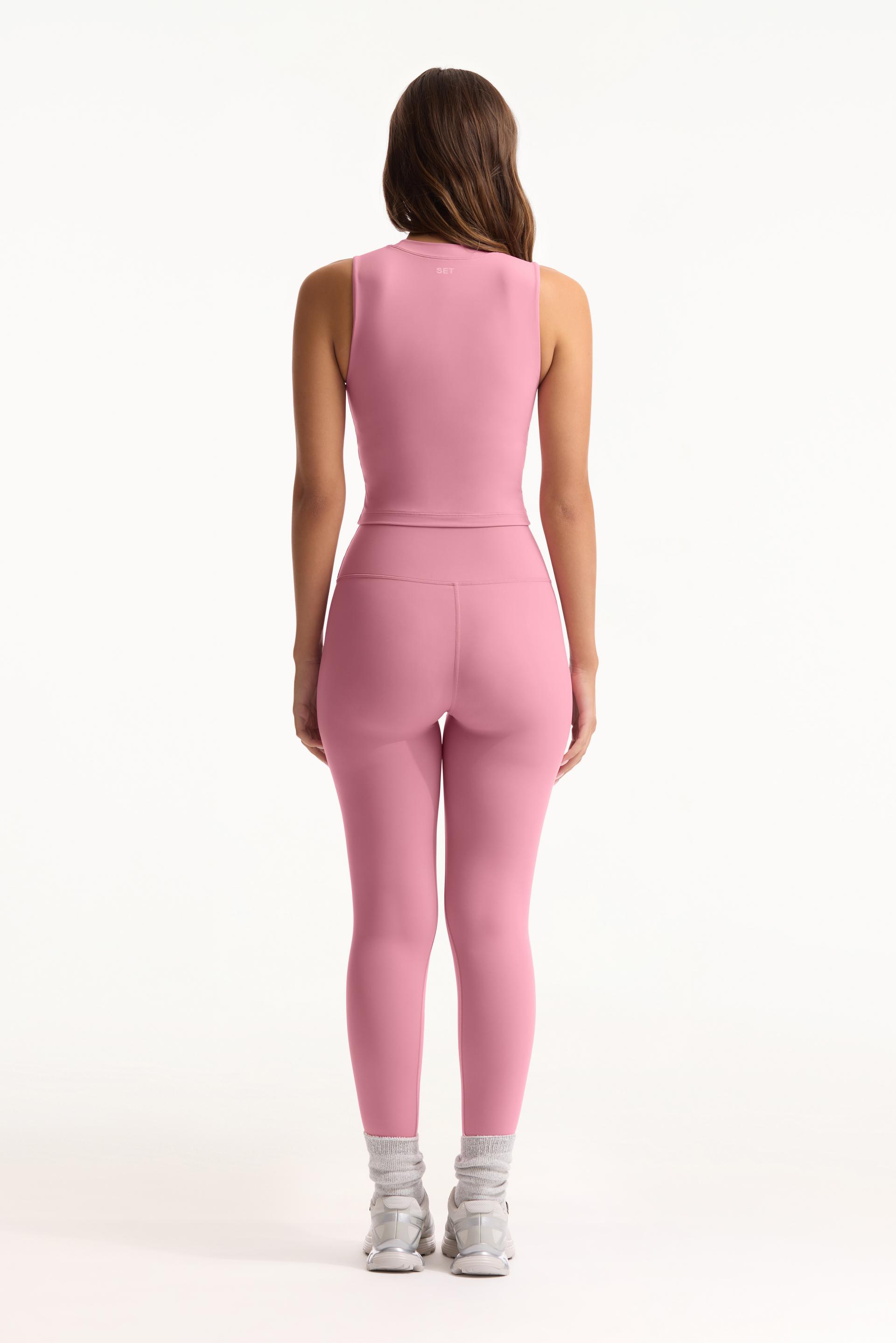 Person wearing a pink jumpsuit on a white background