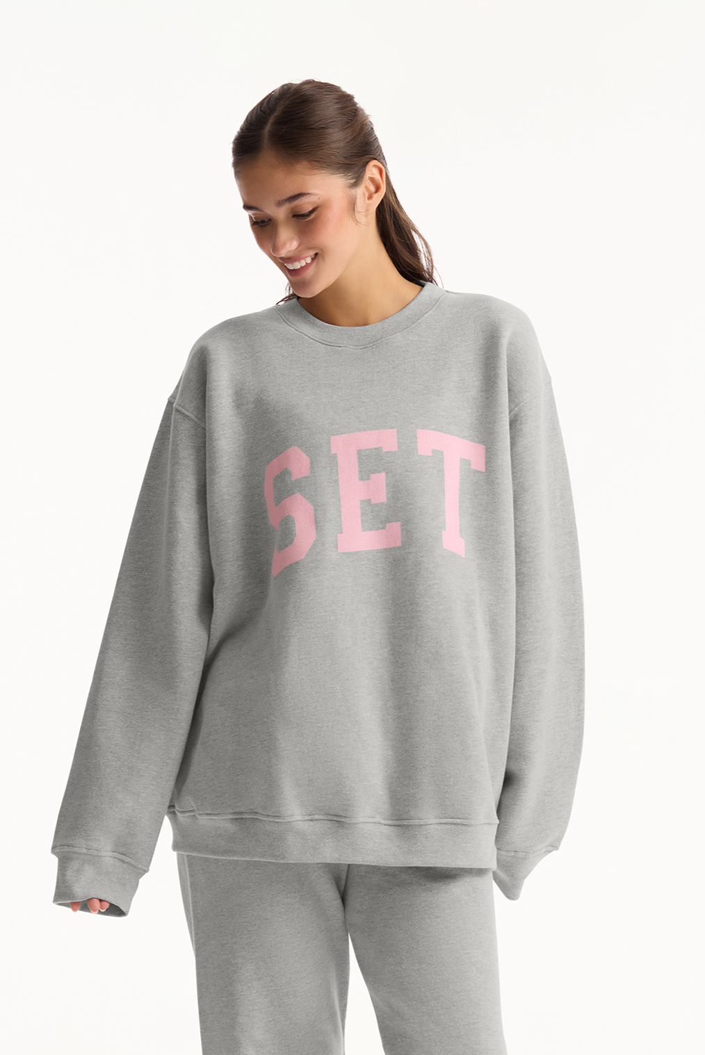 Person wearing a gray sweatshirt with 'SET' printed in pink on a white background 