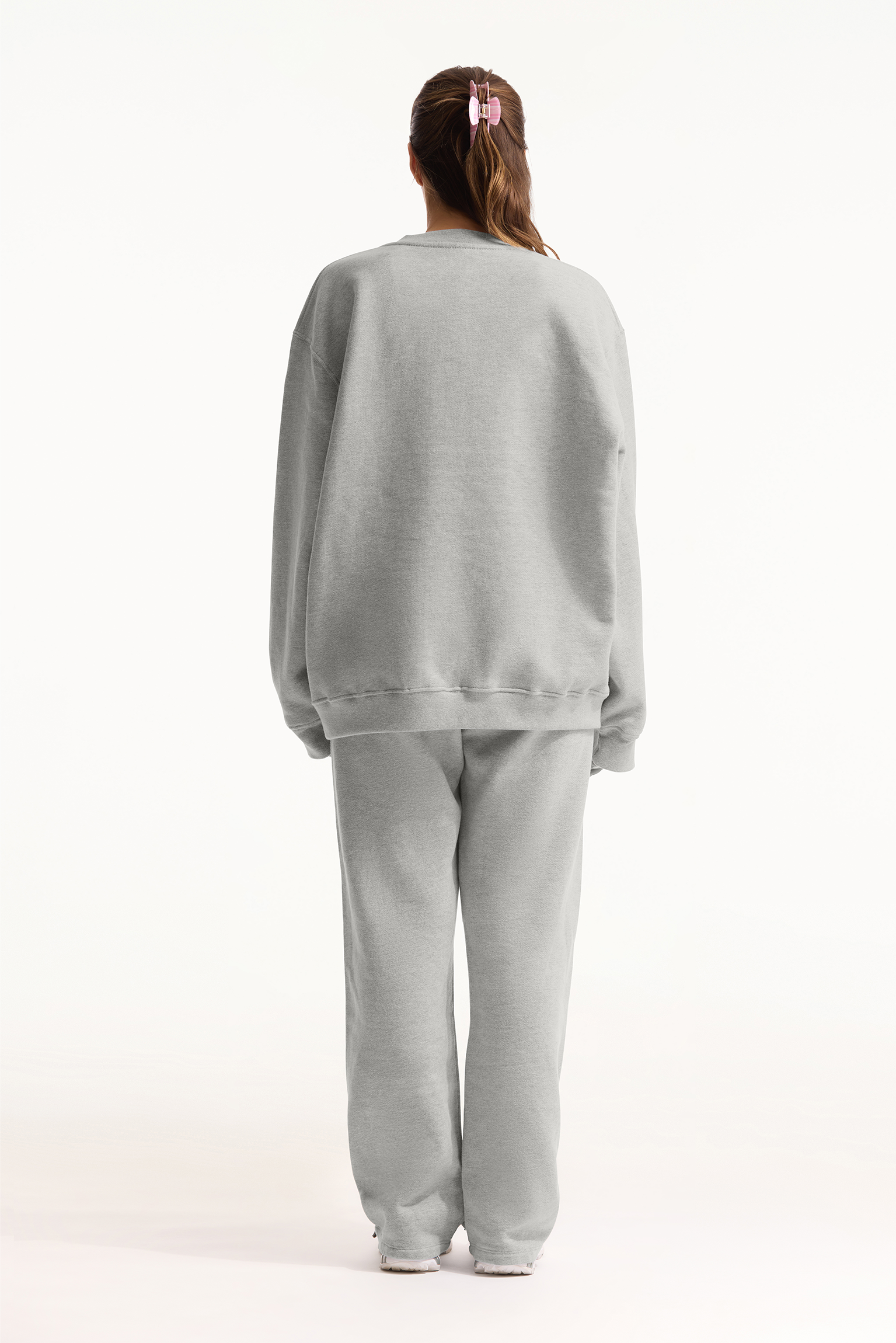 Person wearing a light gray sweatshirt and pants set on a white background
