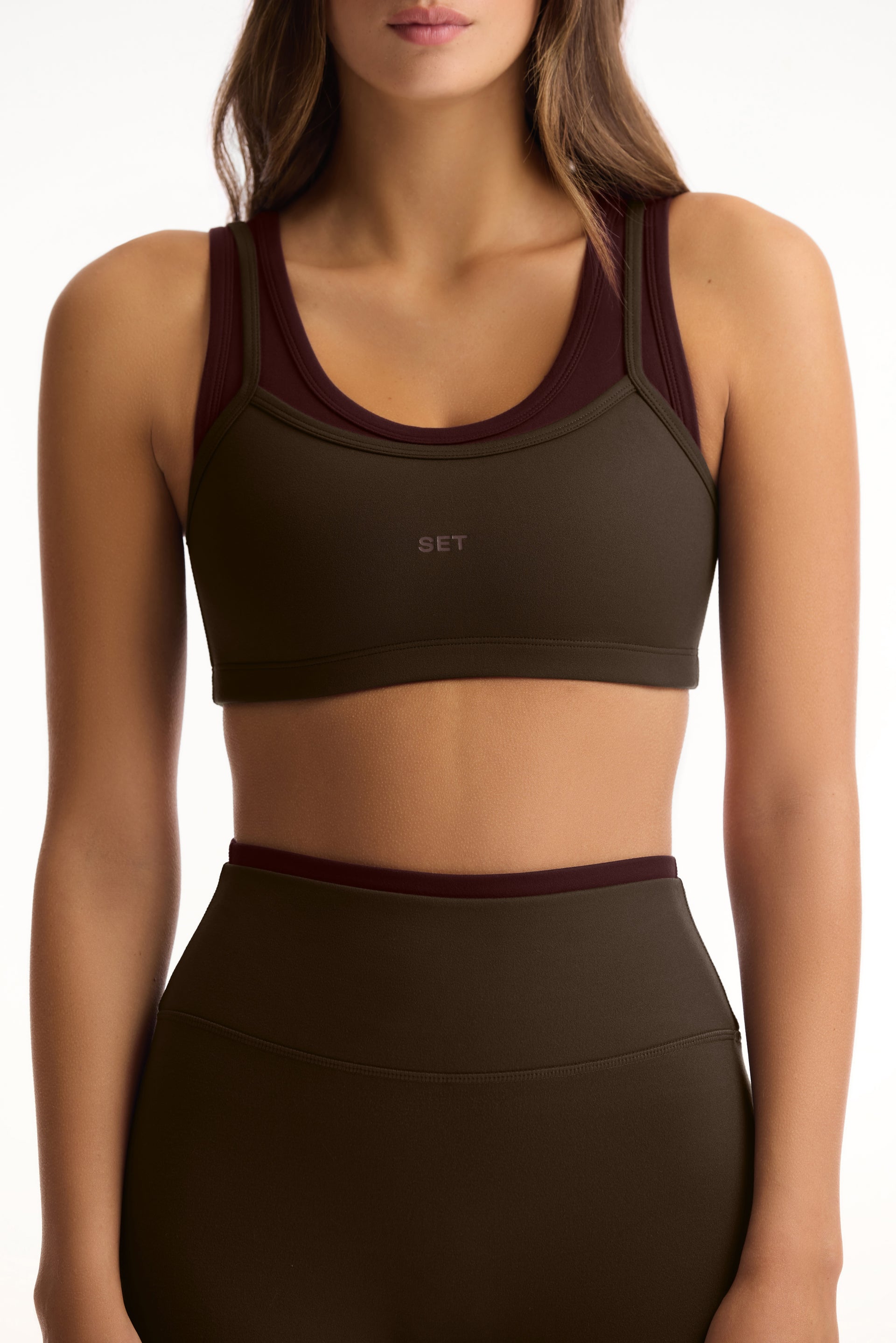 Woman wearing a green sports bra and leggings with a brand logo on a white background