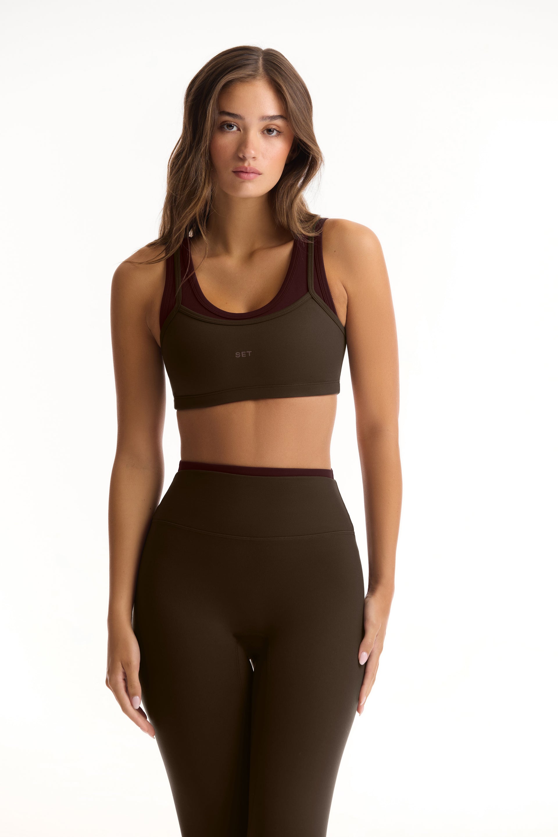 Woman wearing a green sports bra and leggings set on a white background <model-info>Sophie wears a size S and is 5’9½”, 23” waist, 34CD bust.</model-info>