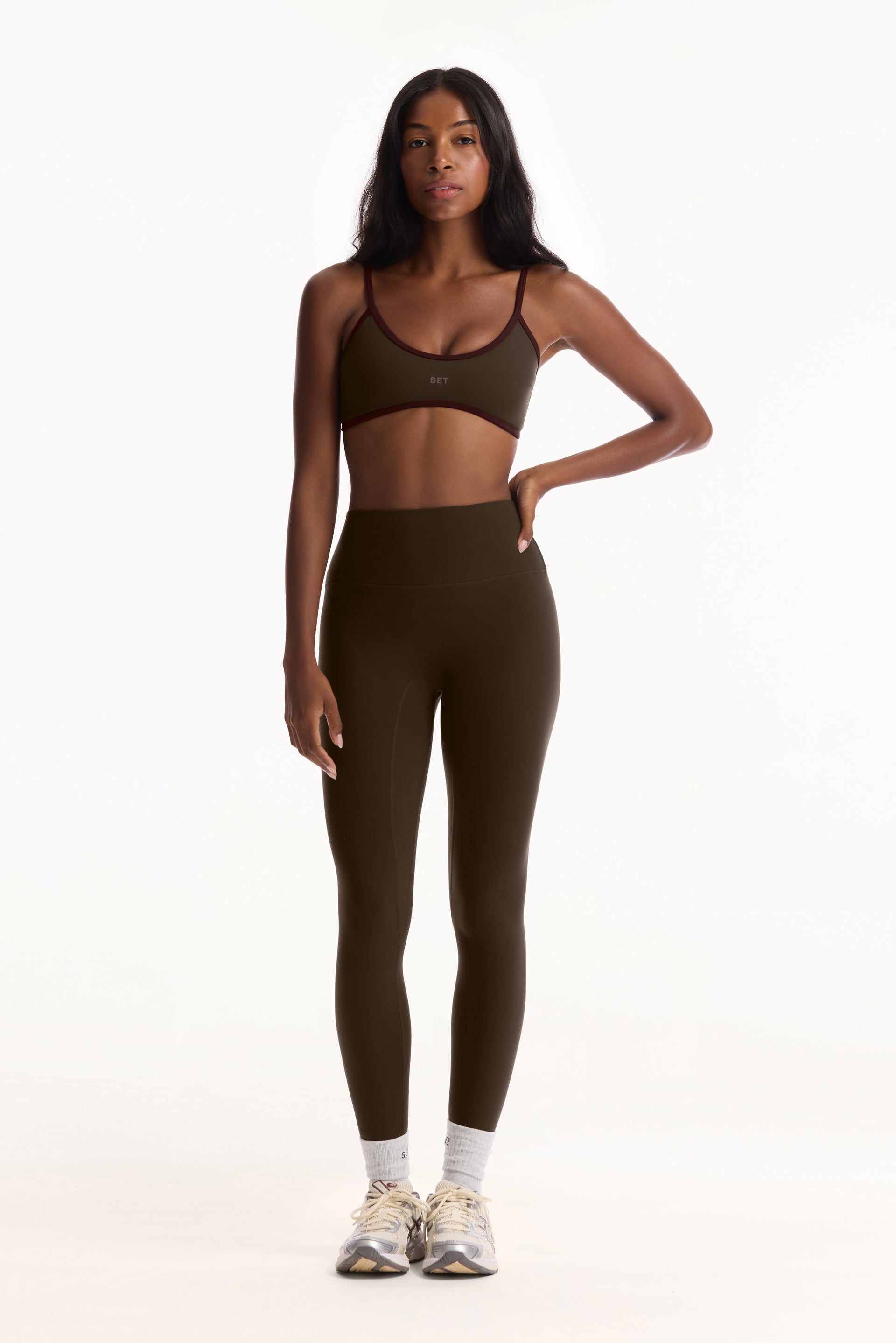 Woman wearing a green sports bra and leggings set on a white background