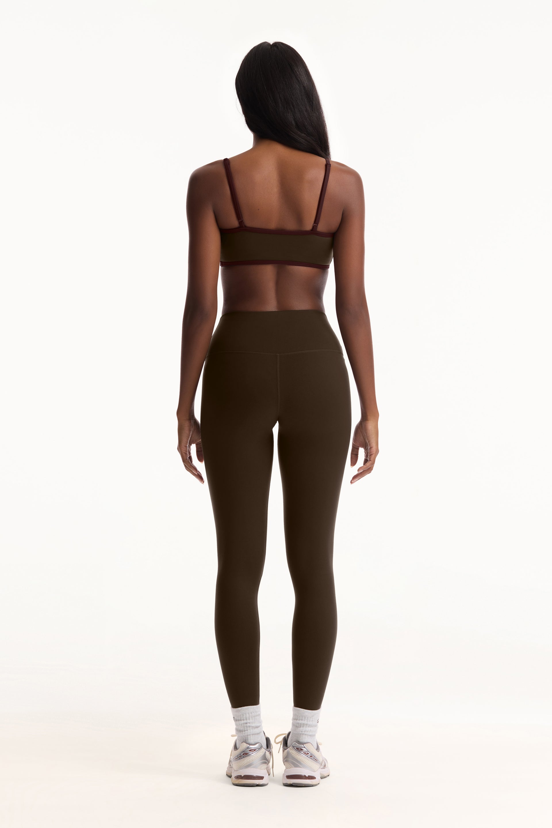 Person wearing a green sports bra and leggings set on a white background