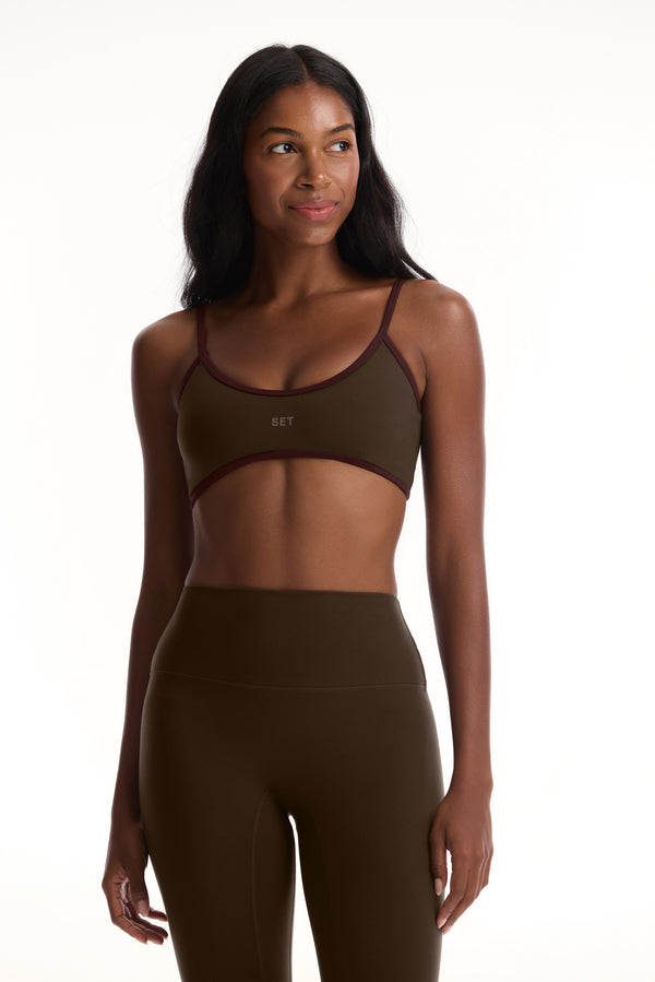 Woman wearing an olive green sports bra and leggings set on a white background 