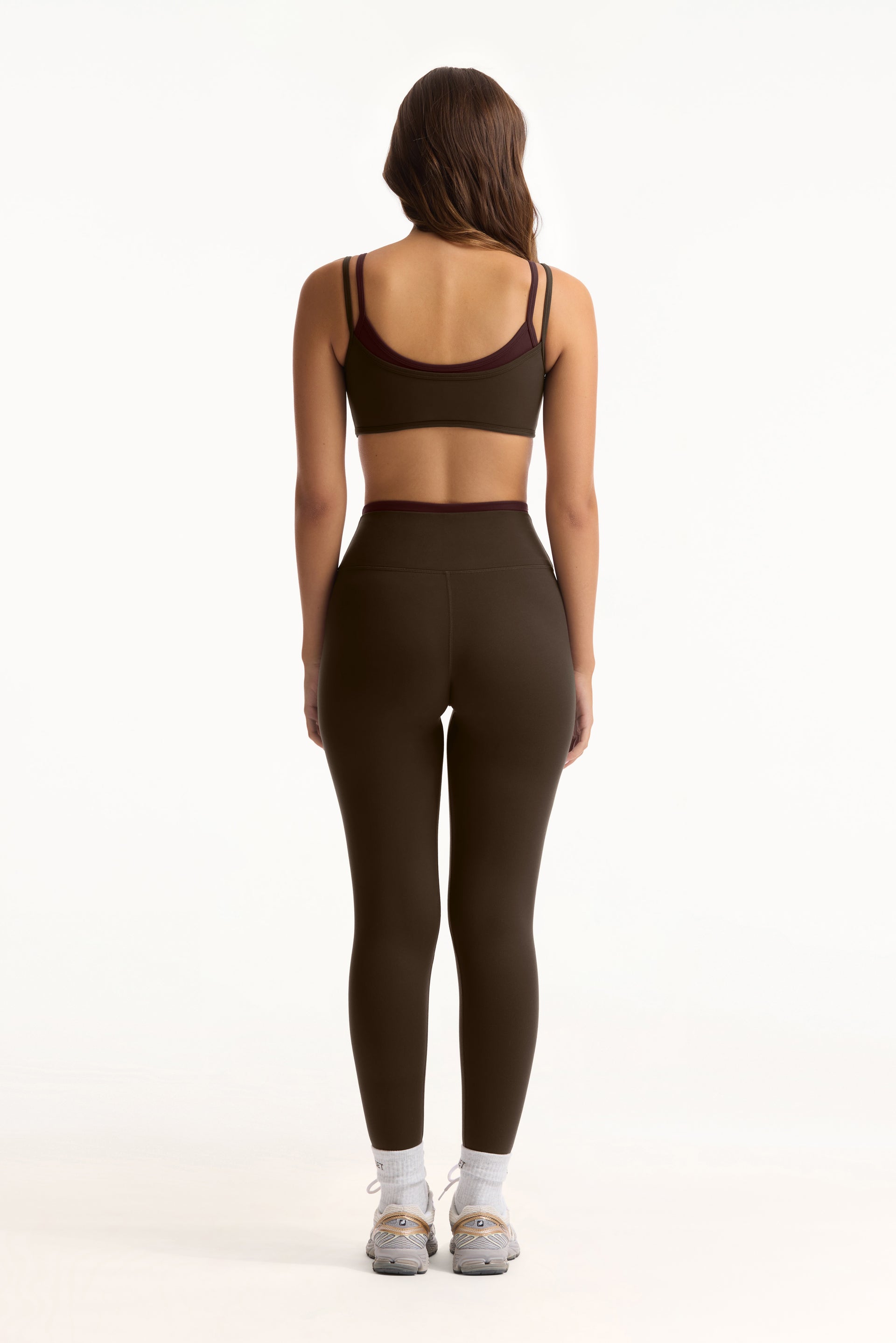 Person wearing a green sports bra and leggings set on a white background