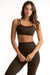 Woman wearing a green sports bra and leggings set on a white background <model-info>Sophie wears a size S and is 5’9½”, 23” waist, 34CD bust.</model-info>