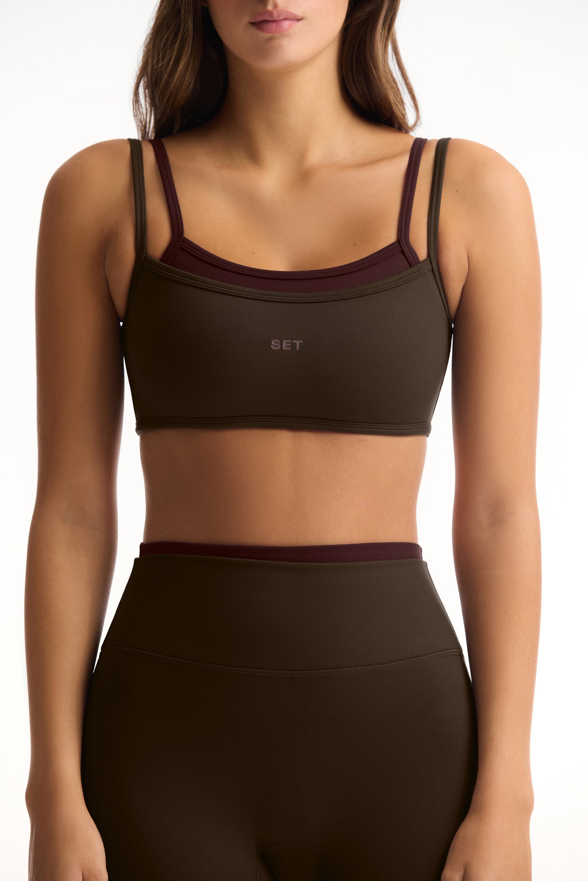 Woman wearing a green sports bra and leggings with a brand logo on a white background